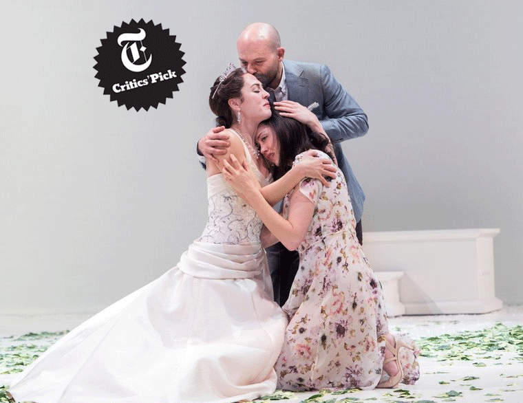 A bride on her knees hugging a woman while a man kisses her forhead