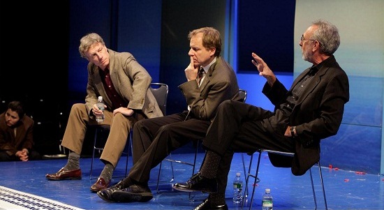 Three people sitting on stage in chairs talking