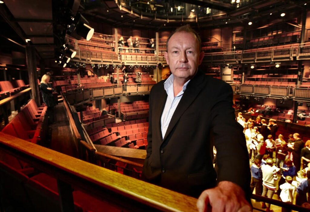 Michael Boyd standing on the balcony with a over view of the theatre behind him.
