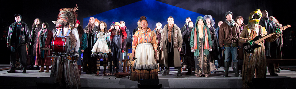 A bunch of actors on stage all dressed in costumes singing.