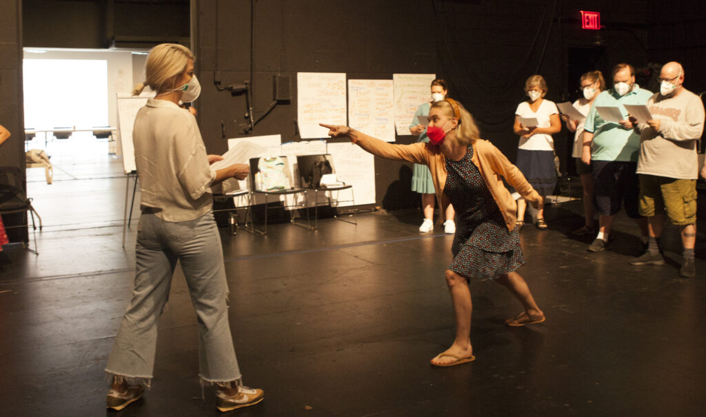 Teacher participants in TFANA's 2022 NEH Institute engage in an acting exercise led by director Claudia Zelevansky. Using text from Measure for Measure, two teachers stand opposite each other onstage at the Polonsky Shakespeare Center, one gesturing towards the other accusingly.