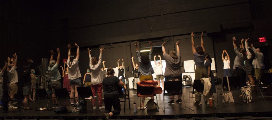 Teachers at TFANA's 2022 NEH Summer Institute engage in a warm-up activity led by faculty. They are in a circle on the stage at the Polonsky Shakespeare Center raising their hands in the air.